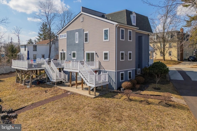 rear view of house with stairs, a shingled roof, mansard roof, and a deck