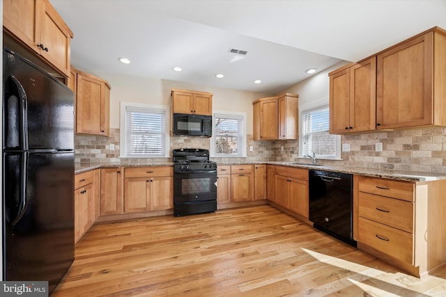 kitchen with light wood-type flooring, black appliances, visible vents, and a sink