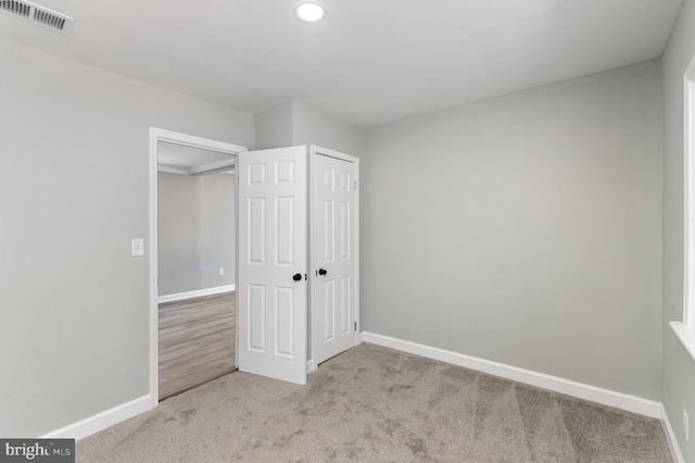 unfurnished bedroom with a closet, baseboards, visible vents, and carpet flooring