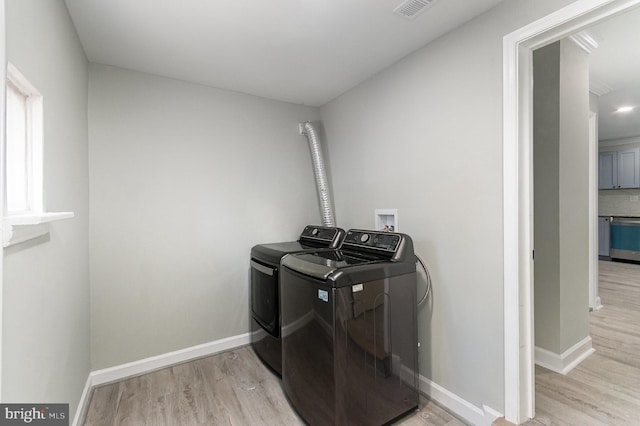 washroom with laundry area, visible vents, baseboards, washing machine and clothes dryer, and light wood-style floors