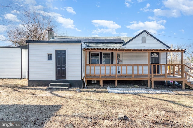 view of front of home featuring roof mounted solar panels and a chimney