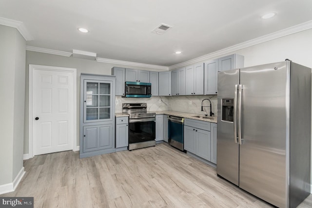 kitchen featuring crown molding, gray cabinets, visible vents, appliances with stainless steel finishes, and a sink