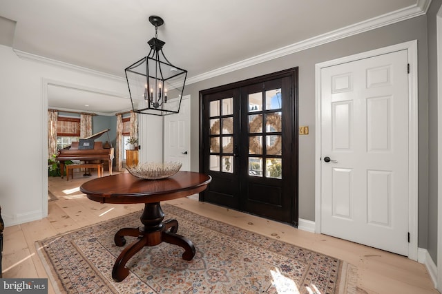 foyer with baseboards, french doors, a notable chandelier, and crown molding