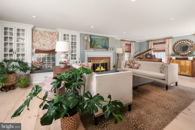 living room featuring light wood-type flooring, a fireplace, and crown molding