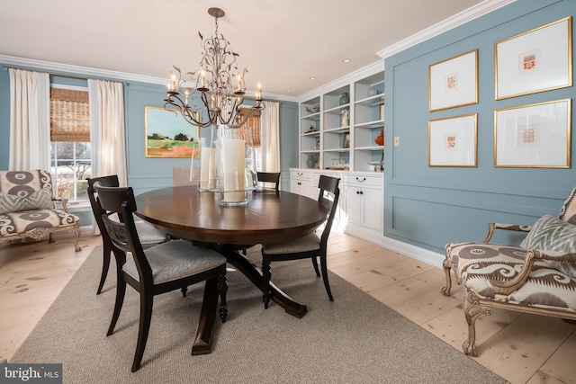 dining space with light wood-style floors, crown molding, built in features, and an inviting chandelier