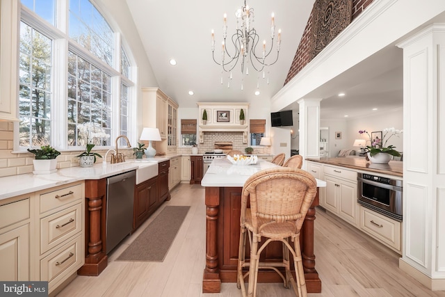 kitchen featuring stainless steel appliances, light wood-style floors, a kitchen breakfast bar, cream cabinetry, and glass insert cabinets