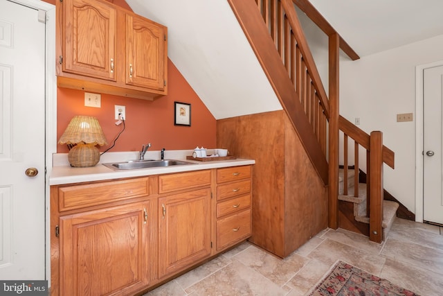 kitchen with light countertops, stone finish floor, a sink, and brown cabinets