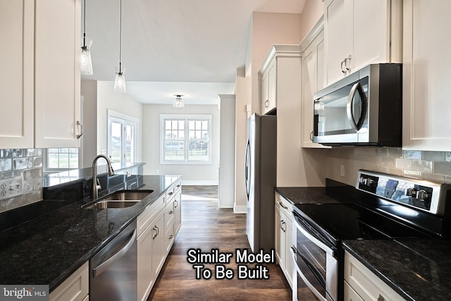 kitchen with hanging light fixtures, white cabinetry, stainless steel appliances, and a sink