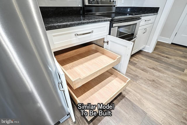 kitchen featuring electric stove, light wood finished floors, dark countertops, and white cabinetry