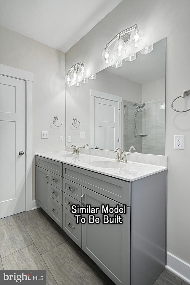 bathroom featuring a sink, double vanity, a shower stall, and baseboards