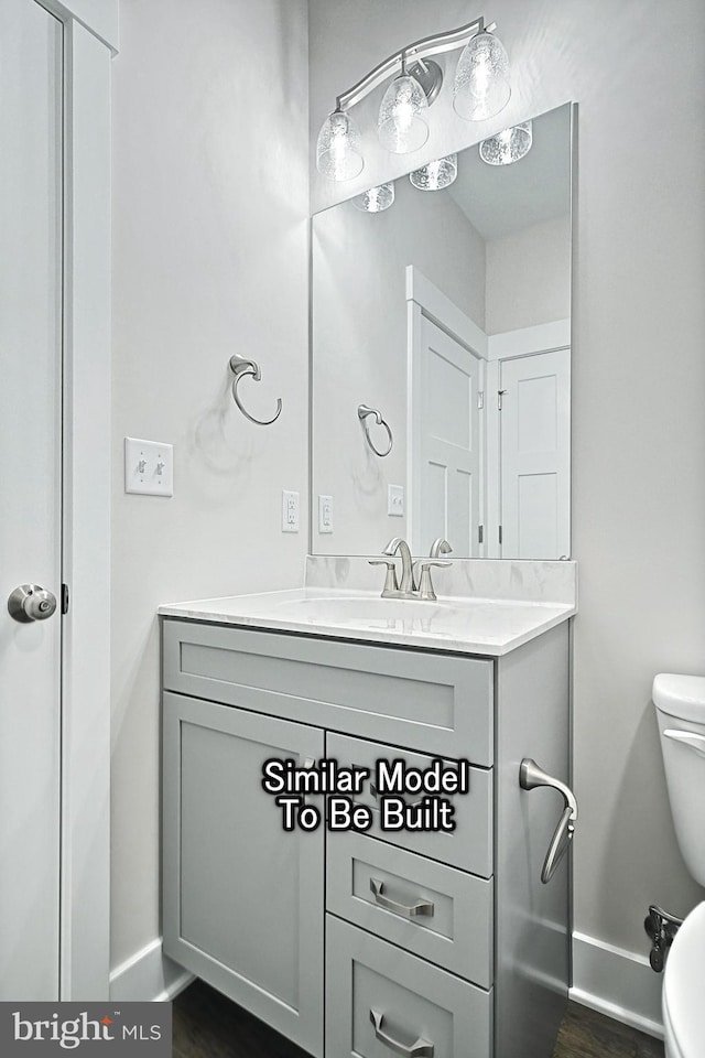 bathroom featuring baseboards, vanity, toilet, and wood finished floors