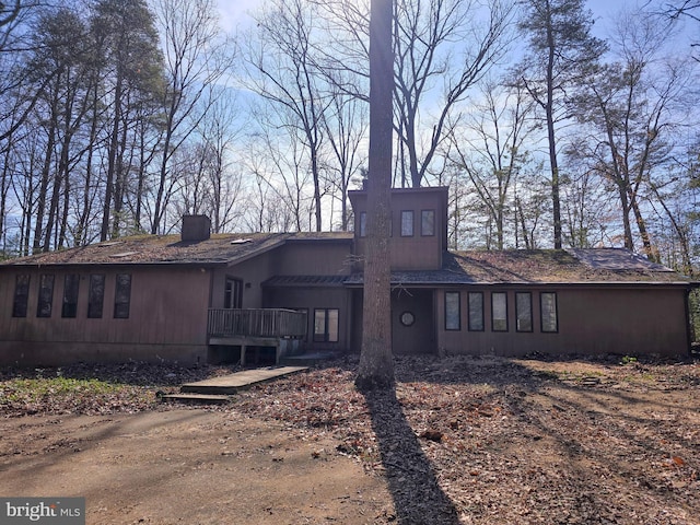 back of property featuring a chimney and a wooden deck