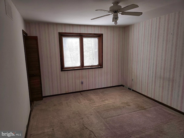 spare room featuring wallpapered walls, visible vents, baseboards, and light colored carpet