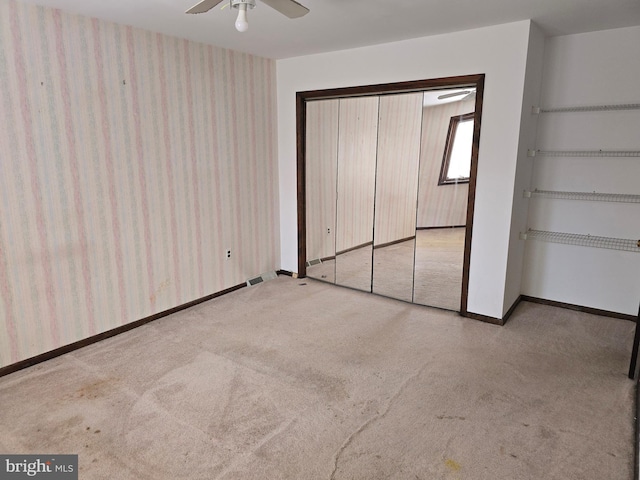 unfurnished bedroom featuring a ceiling fan, light carpet, baseboards, and wallpapered walls