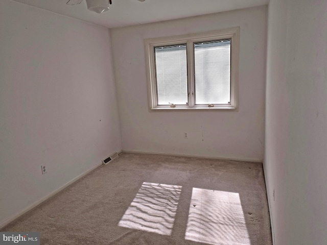 spare room with light carpet, visible vents, and baseboards