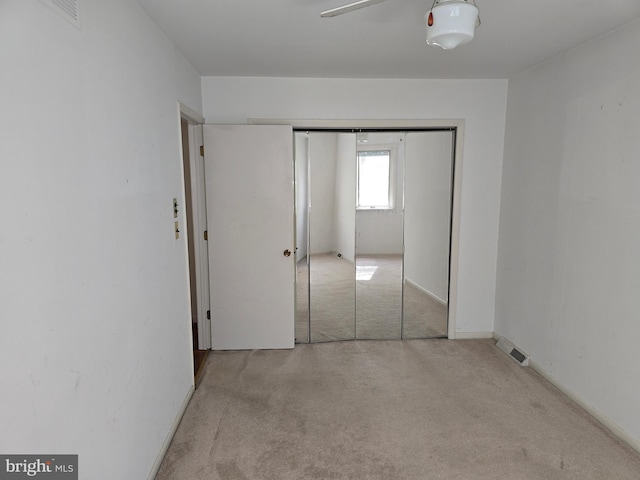 unfurnished bedroom featuring baseboards, a closet, visible vents, and light colored carpet