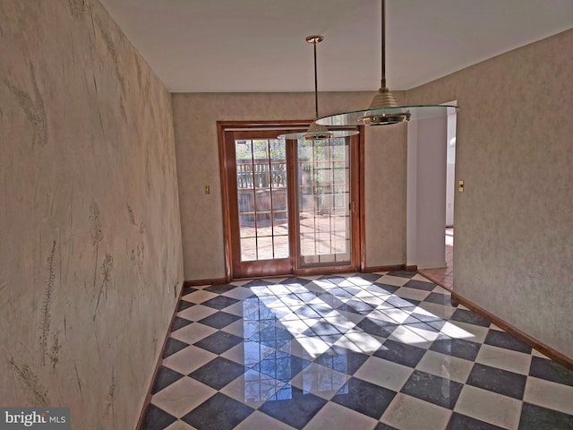 unfurnished dining area featuring dark floors and baseboards