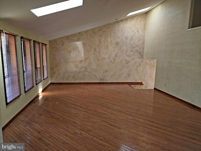 empty room featuring lofted ceiling with skylight and dark wood-style flooring