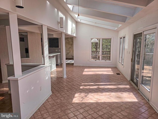 unfurnished sunroom with vaulted ceiling with skylight, plenty of natural light, and visible vents