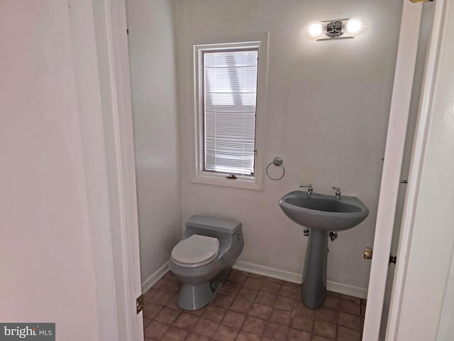 half bath with toilet, baseboards, and a sink