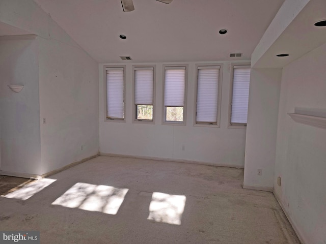 empty room featuring baseboards, visible vents, and vaulted ceiling