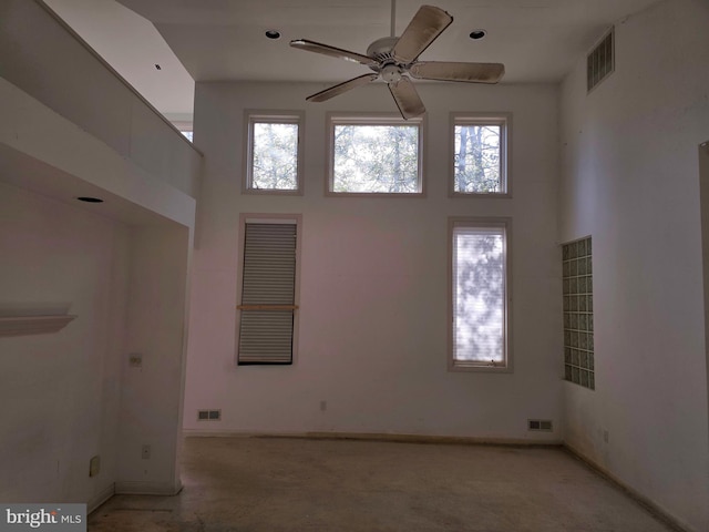 empty room with visible vents, plenty of natural light, and a towering ceiling