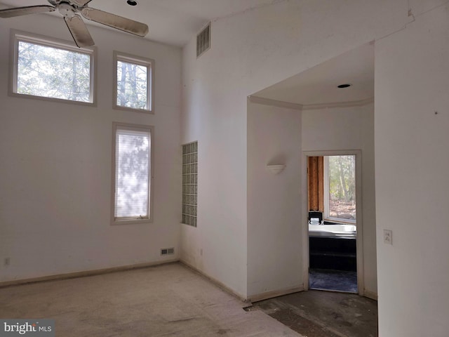 interior space featuring a towering ceiling, baseboards, visible vents, and a ceiling fan