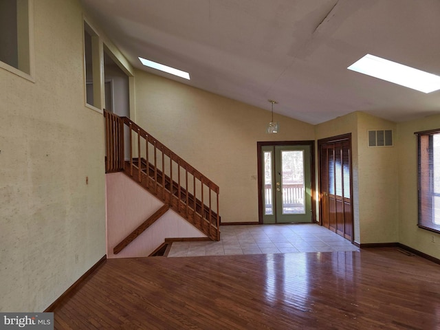 entrance foyer with visible vents, light wood-style floors, vaulted ceiling with skylight, baseboards, and stairs