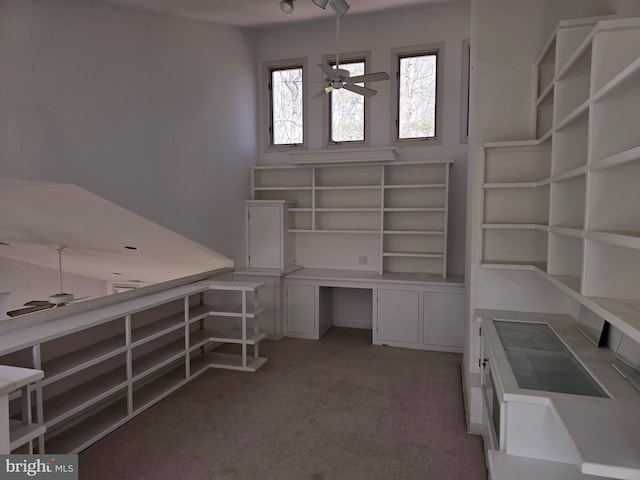 unfurnished office featuring light colored carpet, ceiling fan, and built in study area