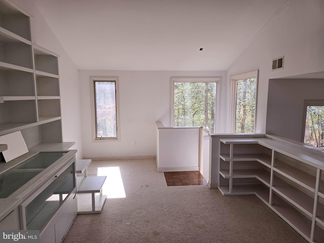 unfurnished office featuring lofted ceiling, visible vents, and a healthy amount of sunlight