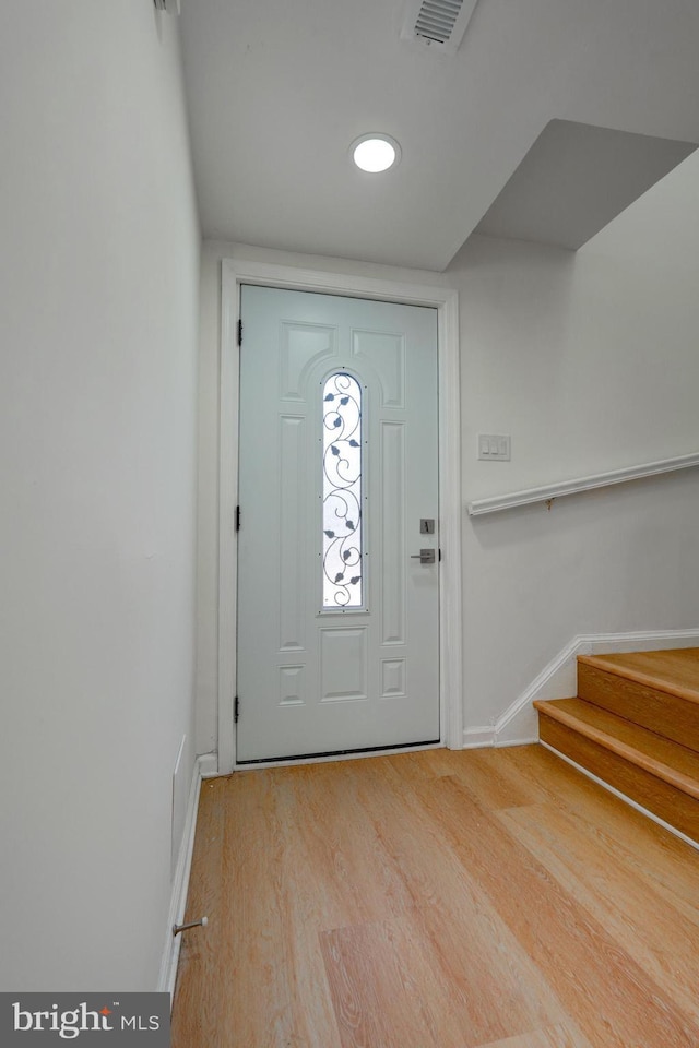 entrance foyer featuring light wood finished floors, baseboards, stairs, and visible vents