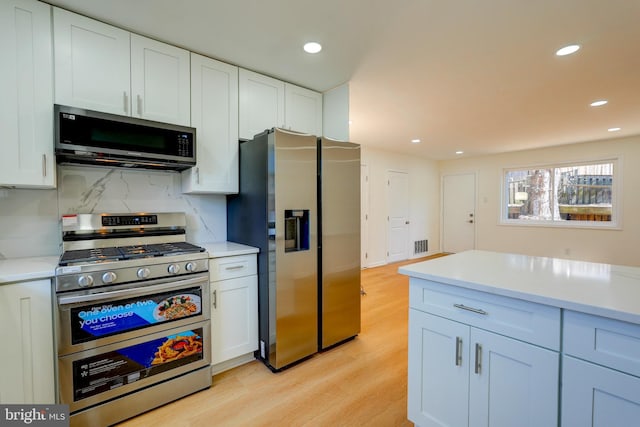 kitchen featuring white cabinets, light wood-style flooring, appliances with stainless steel finishes, light countertops, and recessed lighting