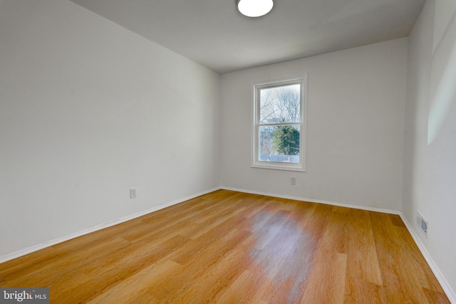 spare room featuring light wood-type flooring and baseboards