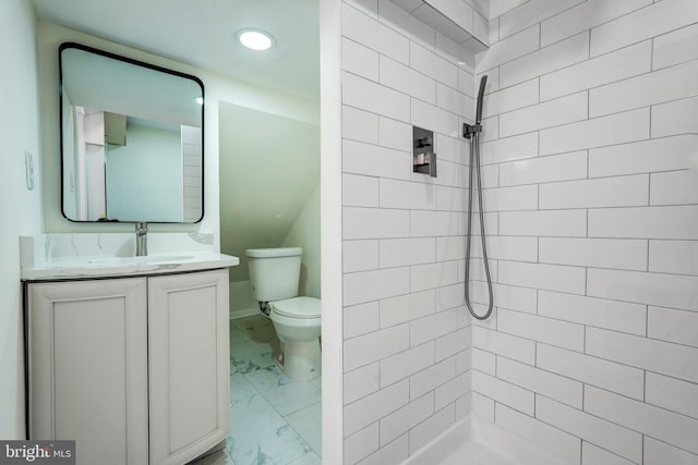 bathroom featuring toilet, marble finish floor, a tile shower, and vanity