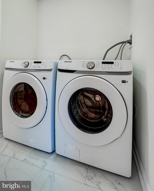 washroom featuring washer and dryer, marble finish floor, and laundry area