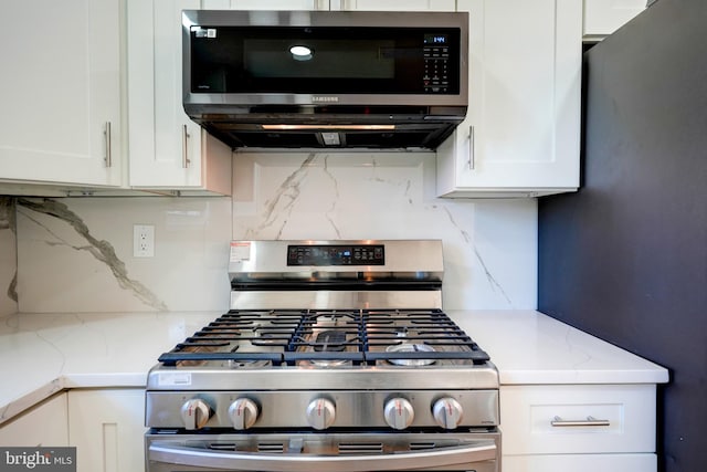 kitchen with stainless steel appliances, tasteful backsplash, light stone countertops, and white cabinets