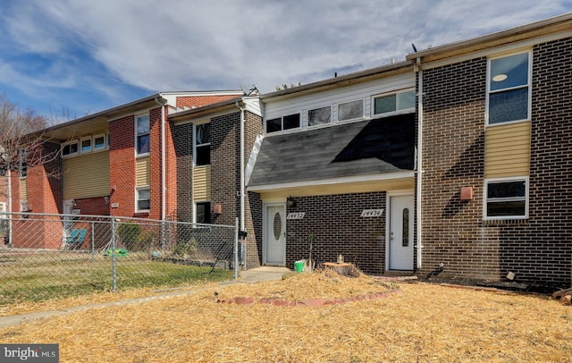 back of house featuring brick siding and fence