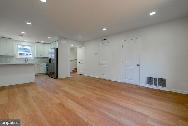 unfurnished living room featuring baseboards, recessed lighting, visible vents, and light wood-style floors