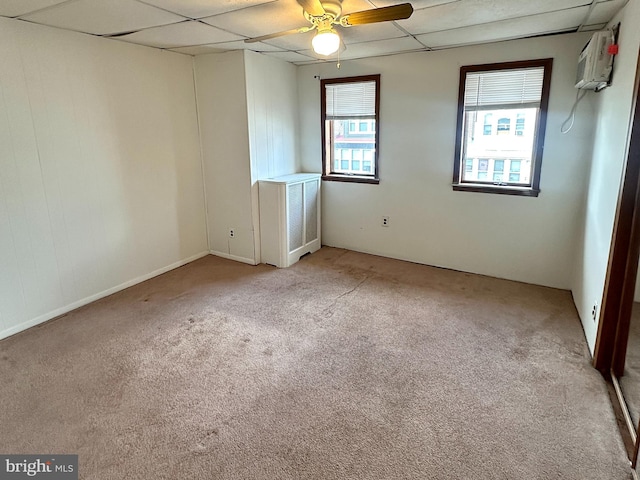 spare room featuring light carpet, a wall mounted AC, and a drop ceiling
