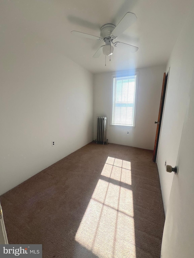 spare room with carpet, radiator, and ceiling fan