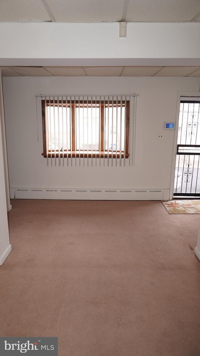 carpeted spare room with a baseboard radiator, plenty of natural light, and a paneled ceiling