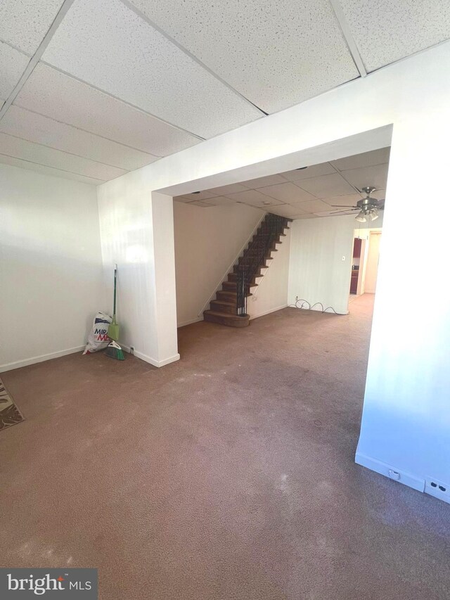 finished below grade area with carpet, a paneled ceiling, baseboards, and stairs