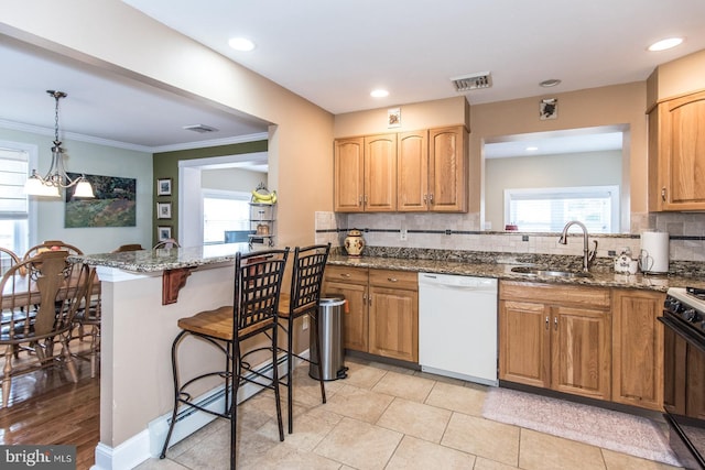 kitchen featuring a sink, visible vents, a kitchen breakfast bar, dishwasher, and gas range