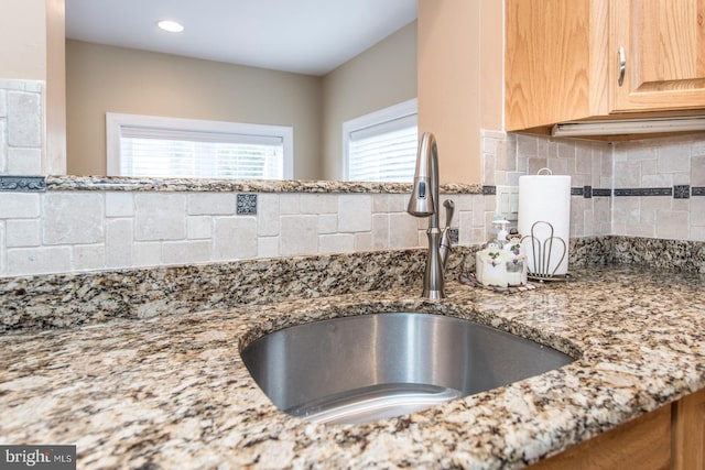 interior space featuring light stone countertops, tasteful backsplash, a sink, and light brown cabinetry