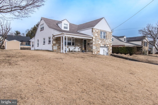 view of front of property featuring an attached garage, stone siding, and roof with shingles