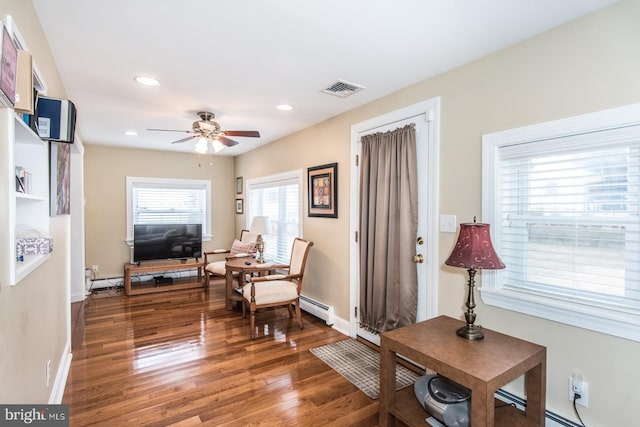 living area with baseboards, visible vents, a baseboard heating unit, and wood finished floors