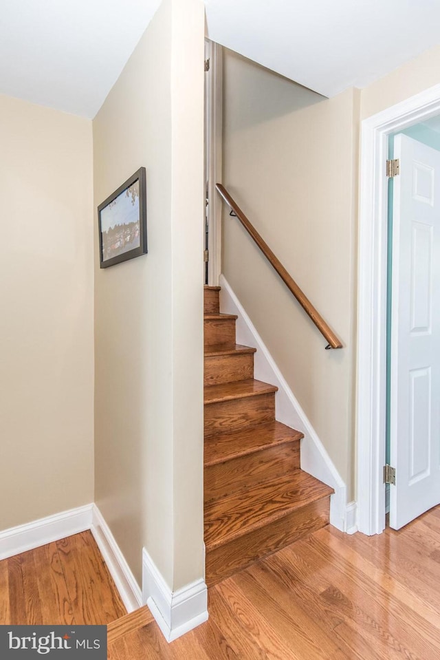 staircase featuring baseboards and wood finished floors