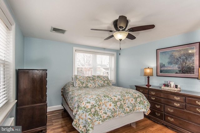 bedroom with a ceiling fan, visible vents, baseboards, and wood finished floors