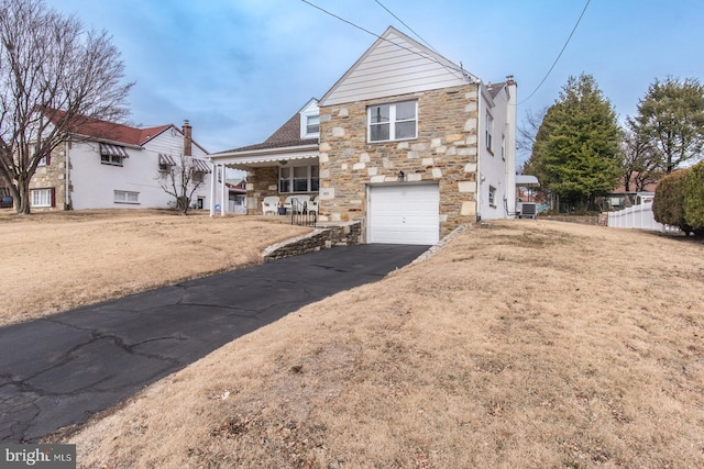 view of front of house with aphalt driveway, a porch, fence, a garage, and stone siding