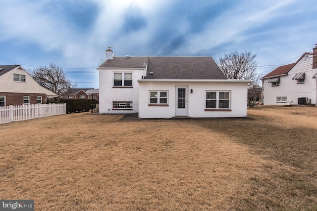 back of house featuring a lawn, a chimney, fence, cooling unit, and stucco siding